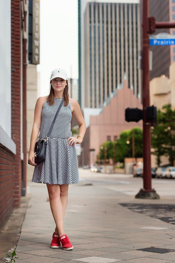 Caroline Harper Knapp of HOUSE of HARPER styles a navy stripe dress with a baseball cap and red tennis shoes.